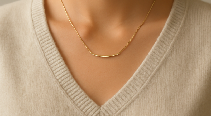 collier minimal posé sur pull col V